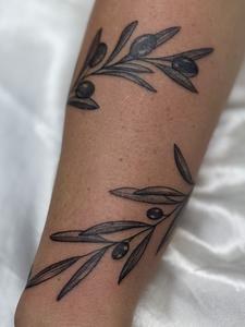 Olive branch fine line tattoo wrapping the forearm